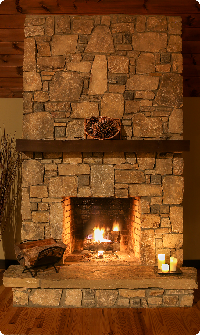 Stone fireplace with lit candles and fire.